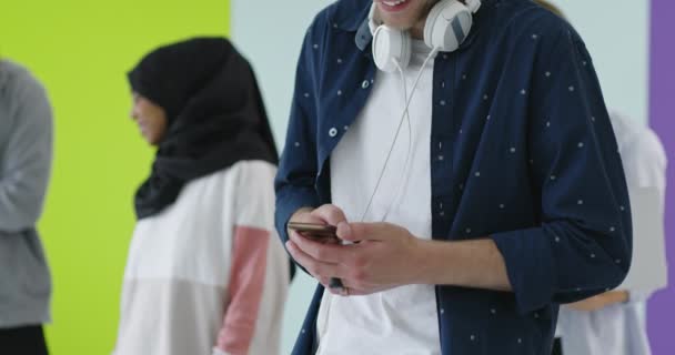 Cep telefonu kullanan çok kültürlü bir arkadaş grubu. Öğrenciler sıraya girip renk duvarının üzerinden akıllı telefonlara yazı yazıyorlar. — Stok video