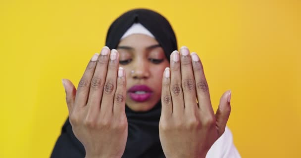 Ung vacker afrikansk amerikansk flicka bär muslim hijab över isolerad gul bakgrund be med händerna tillsammans — Stockvideo