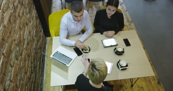 Grupa młodych ludzi siedząca w kawiarni, rozmawiająca i ciesząca się, widok z góry, biznesmeni prowadzący spotkanie — Wideo stockowe
