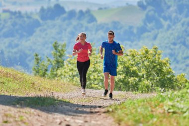 Çiftler, köy yolunda koşarken sağlıklı bir yaşam tarzının keyfini çıkarıyorlar.