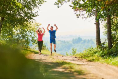 Çiftler, köy yolunda koşarken sağlıklı bir yaşam tarzının keyfini çıkarıyorlar.