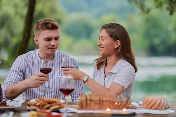 Piknik yaparken dışarıda kırmızı şarap kadehi içen çiftler.