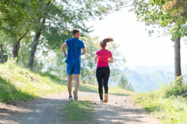 Çiftler, köy yolunda koşarken sağlıklı bir yaşam tarzının keyfini çıkarıyorlar.