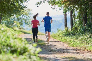 Çiftler, köy yolunda koşarken sağlıklı bir yaşam tarzının keyfini çıkarıyorlar.