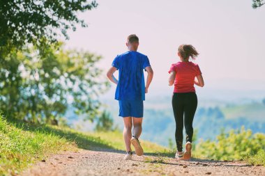 Çiftler, köy yolunda koşarken sağlıklı bir yaşam tarzının keyfini çıkarıyorlar.