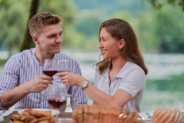 Piknik yaparken dışarıda kırmızı şarap kadehi içen çiftler.