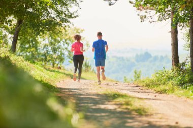 Çiftler, köy yolunda koşarken sağlıklı bir yaşam tarzının keyfini çıkarıyorlar.