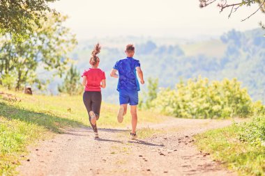 Çiftler, köy yolunda koşarken sağlıklı bir yaşam tarzının keyfini çıkarıyorlar.