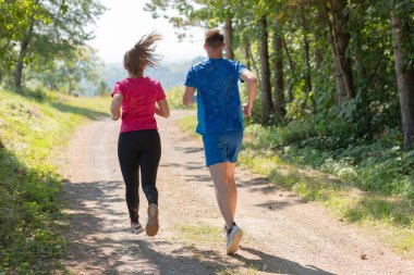 Çiftler, köy yolunda koşarken sağlıklı bir yaşam tarzının keyfini çıkarıyorlar.