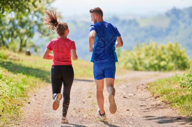 Çiftler, köy yolunda koşarken sağlıklı bir yaşam tarzının keyfini çıkarıyorlar.