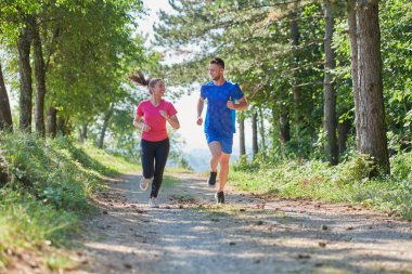 Çiftler, köy yolunda koşarken sağlıklı bir yaşam tarzının keyfini çıkarıyorlar.