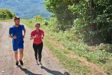 Çiftler, köy yolunda koşarken sağlıklı bir yaşam tarzının keyfini çıkarıyorlar.