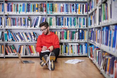 Öğrenciler bir dizüstü bilgisayar ve okul kütüphanesi kullanıyor.