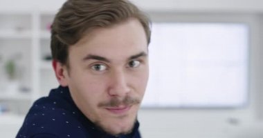 Kanepede oturan ve modern evde gülümseyen bir adam.