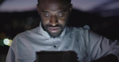 Gece vakti akıllı telefon kullanan Afro-Amerikalı adam.