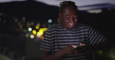 Gece vakti akıllı telefon kullanan Afro-Amerikalı adam.