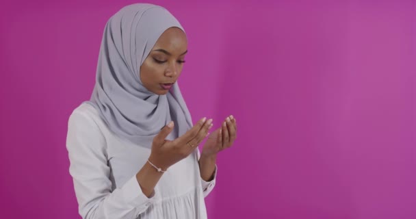 現代アフリカのイスラム教徒の女性は、カラフルな背景で神に伝統的な祈りをします — ストック動画