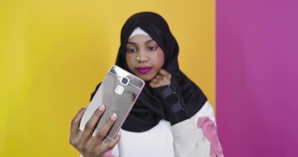 Retrato de una mujer musulmana africana sonriente, tomando selfie en un teléfono inteligente — Vídeos de Stock