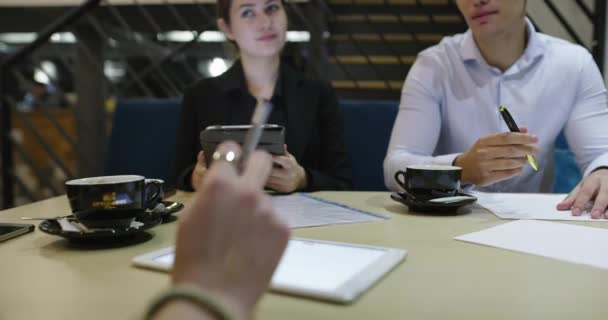 Gropu de gente de negocios que se reúne en la cafetería y trabaja en el primer plano del proyecto en las manos — Vídeo de stock