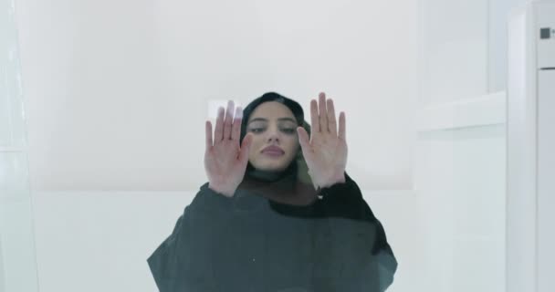 Ближневосточная арабская мусульманка в традиционной хиджабской одежде молится на стеклянном полу — стоковое видео