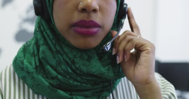 Gros plan de la femme d'affaires islamique heureuse avec hijab portant un casque tout en se tenant dans le bureau moderne — Video