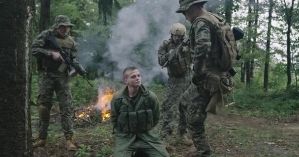 Terrorista foglyokat ejtő és terroristaellenes milíciát folytató katonák sűrű erdőben füsttel a háttérben — Stock videók
