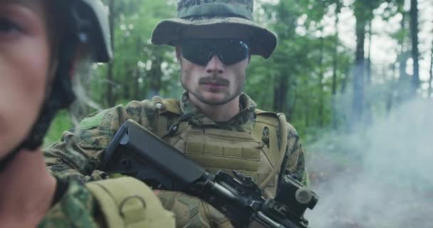 Trupp von Soldaten patrouilliert durch das Waldgebiet, Team mit männlichen und weiblichen Soldaten in dichtem Wald mit Rauch im Hintergrund — Stockvideo