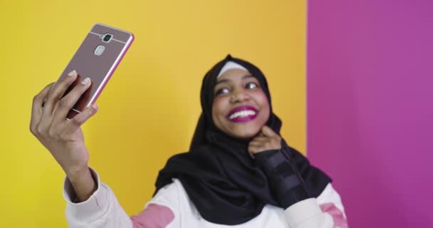 Retrato de una mujer musulmana africana sonriente, tomando selfie en un teléfono inteligente — Vídeos de Stock
