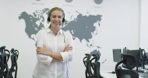 Hermosa mujer operadora joven de pie y con auriculares en el espacio de oficina brillante — Vídeos de Stock