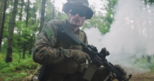 Сучасний солдат з рушницею в густому лісі з димом на фоні — стокове відео