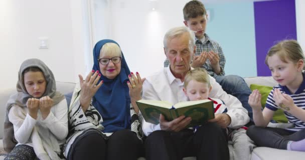 Muslimische Familie Generationen Großeltern lesen Koran mit Enkeln zu Hause — Stockvideo