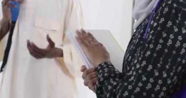 Bir grup mutlu Afrikalı öğrenci sohbet ediyor ve takım buluşması yapıyor. Ev ödevi için birlikte çalışıyorlar. Geleneksel Müslüman başörtüsü giyen kızlar.