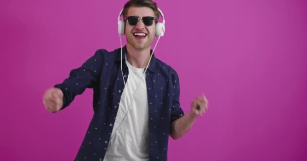 Uomo che balla e sorride sullo sfondo a colori mentre ascolta musica — Video Stock
