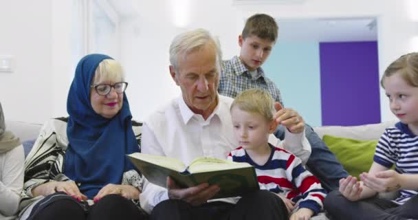 Familia musulmana generaciones abuelos leyendo el Corán con nietos en casa — Vídeo de stock