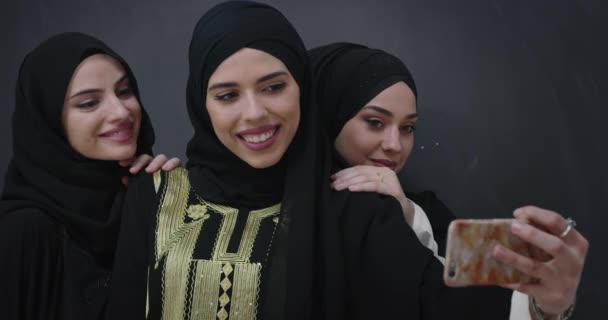 Grupa młodych pięknych muzułmanek w modnej sukience z hidżabem przy użyciu telefonu komórkowego biorąc selfie — Wideo stockowe