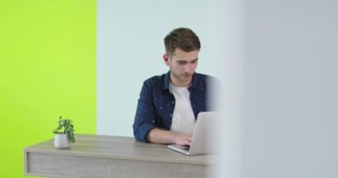 Serbest kariyer, gülen adam evde dizüstü bilgisayarda çalışıyor..