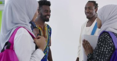Bir grup mutlu Afrikalı öğrenci sohbet ediyor ve takım buluşması yapıyor. Ev ödevi için birlikte çalışıyorlar. Geleneksel Müslüman başörtüsü giyen kızlar.