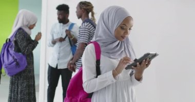 Arkaplanda arkadaş grubu olan Afrikalı kız öğrenci geleneksel İslami tesettüre bürünmüş.