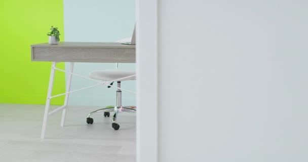 Skrivbord med bärbar dator stående på hemmakontoret framför en tom vägg — Stockvideo