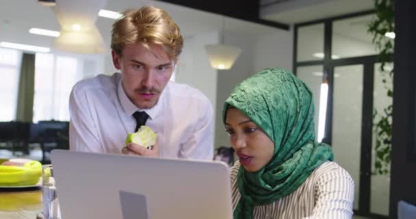Μαύρη γυναίκα με μαντίλα συνάντηση επιχειρηματίας σε casual startup γραφείο, ο άνθρωπος τρώει μήλο κατά τη συνάντηση — Αρχείο Βίντεο