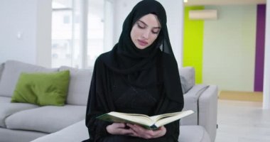 Kadın iftar yemeğinden önce kanepede Kur 'an okuyor evde bir Ramazan bayramı sırasında