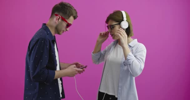 Boldog nő vagy tinédzser lány fülhallgatóban zenét hallgat okostelefonról a barátja választja — Stock videók