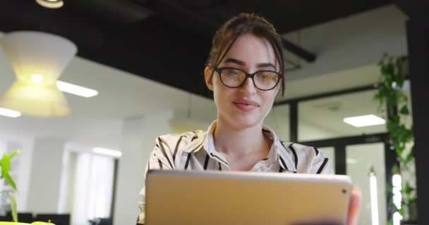 Женщина в очках с планшетом в офисе стартапа — стоковое видео