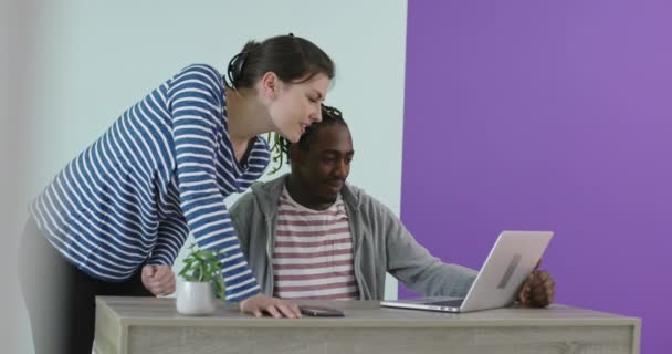 Positivt leende man och kvinna nära arbetsplatsen med laptop samarbetar i kontor — Stockvideo
