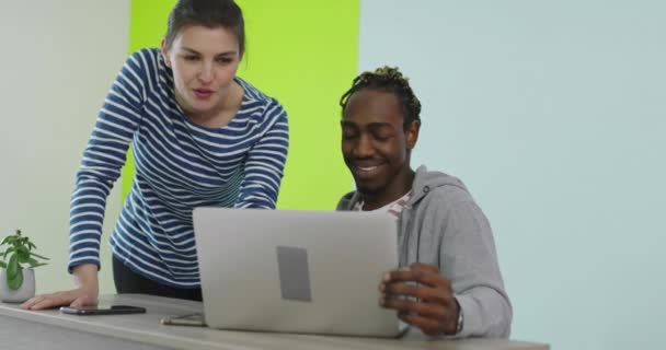 Homem e mulher sorridentes positivos perto do local de trabalho com laptop cooperando no escritório — Vídeo de Stock