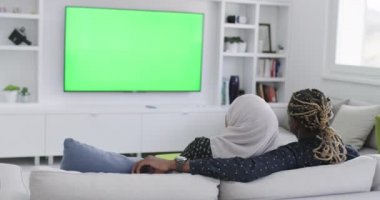 Kanepede Afrikalı bir çiftle yeşil ekran televizyon.