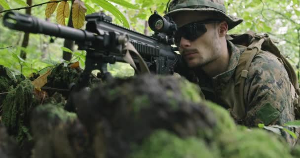 Tam teçhizatlı asker kamuflaj üniforması giyip düşmana saldırıyor, yoğun ormanda tüfeği ateşliyor. — Stok video
