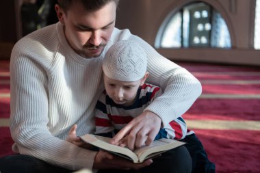  Baba oğul camide dua ediyor ve kutsal kitap Kuran 'ı birlikte okuyorlar. İslam eğitimi kavramı.