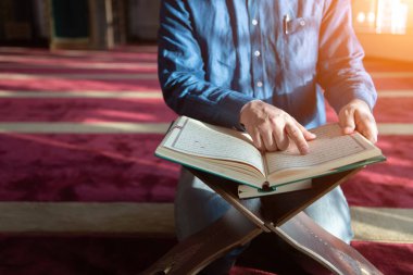 Müslüman adam camide tek başına Allah 'a dua ediyor ve kutsal kitap okuyor.