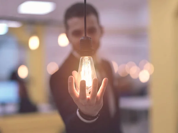 Businessman holding hand around light bulb — Stock Photo, Image